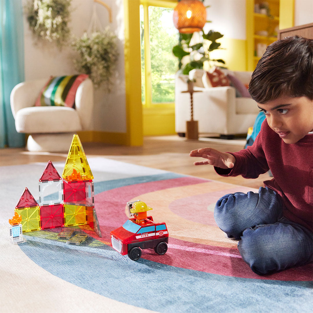 Een kind speelt op de grond met de Magna-Tiles Fire Rescue bouwset en de brandweerwagen.