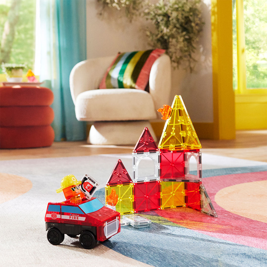 Magna-Tiles Fire Rescue bouwset met brandweerwagen en gebouw van magnetische tegels op een kleurrijk vloerkleed.