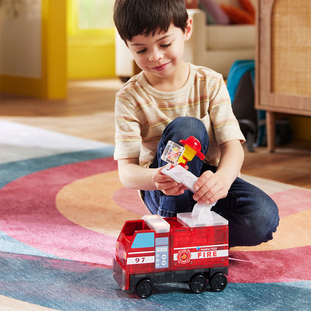 Een kind speelt met de Magna-Tiles brandweerwagen en de brandweerman figuur.