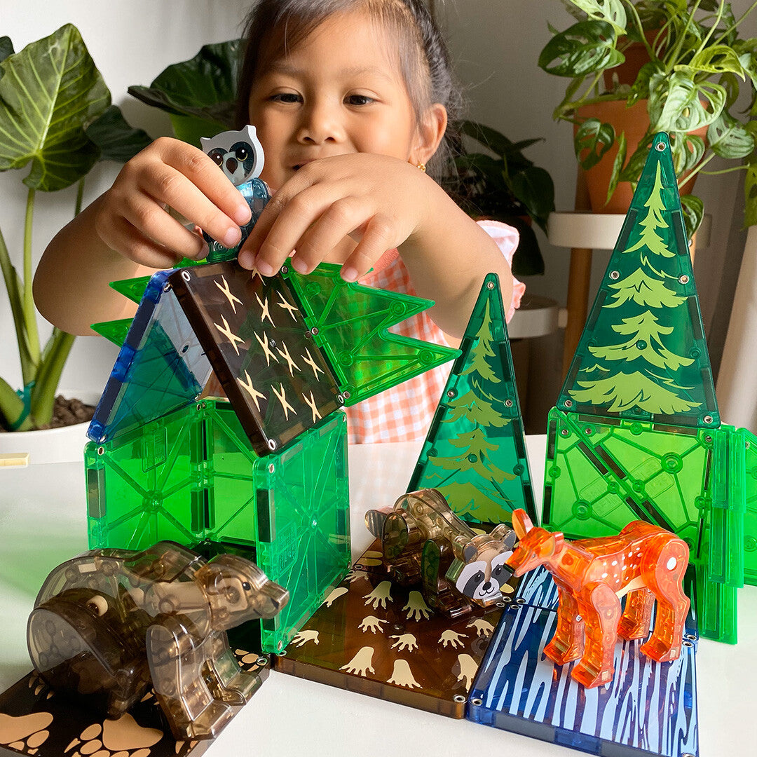 Een kind speelt met de Magna-Tiles Forest Animals bouwset, waarbij een uil op een magnetische boomstructuur wordt geplaatst.