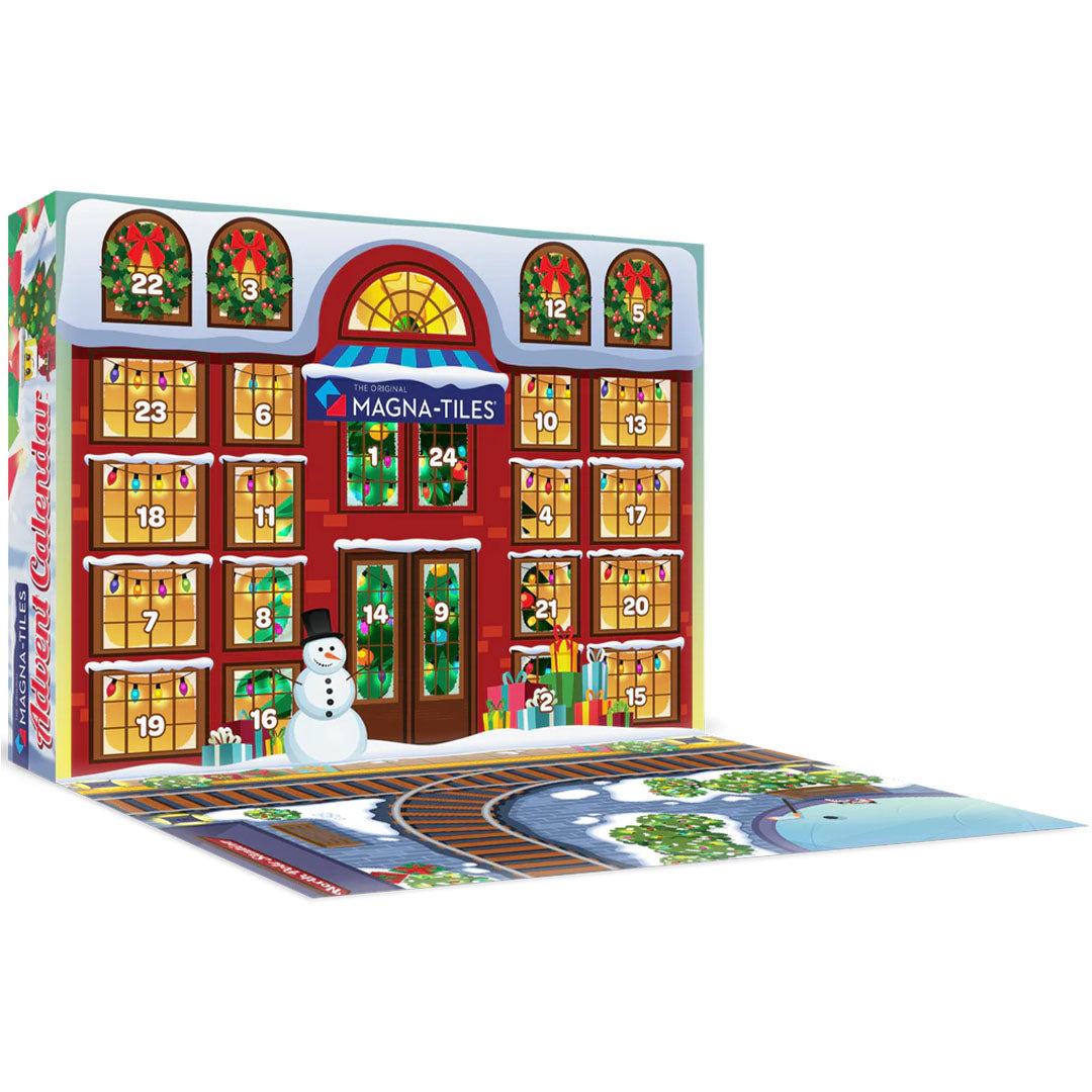 De opengeklapte verpakking van de Magna-Tiles adventskalender toont een gebouw met genummerde ramen en een besneeuwd straatbeeld met spoorrails.