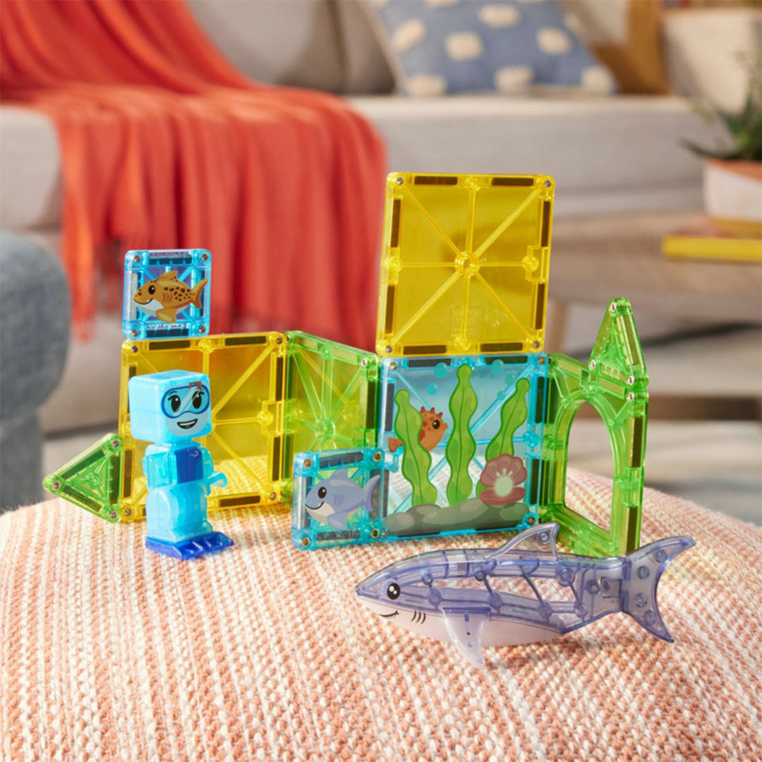 De Magna-Tiles Shark Dive magnetische tegels bouwset met een duiker en haai, op een poef in een woonkamer.