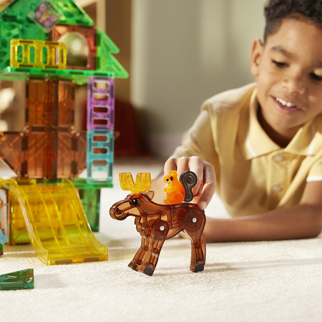 Een jongen speelt met een eekhoornfiguur op een elandfiguur van de Magna-Tiles Treetop Adventure magnetische tegels bouwset.