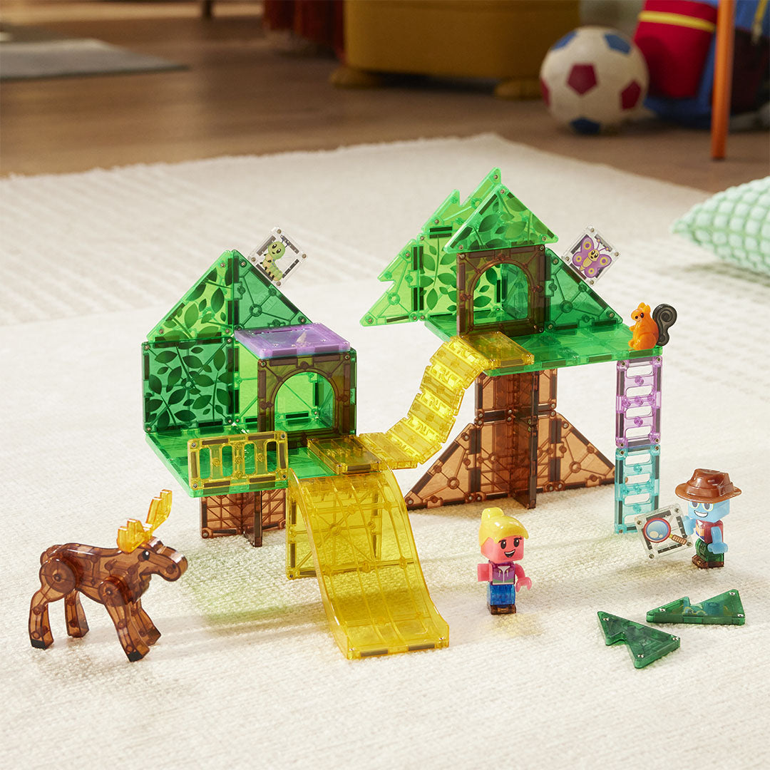De Magna-Tiles Treetop Adventure magnetische tegels bouwset is opgebouwd als een boomhut met glijbanen en figuren op een vloerkleed.
