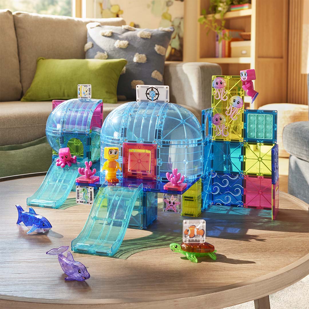 De Magna-Tiles Undersea Adventure bouwset is opgebouwd op een houten tafel, met een onderwaterwereld van magnetische tegels en zeedieren.