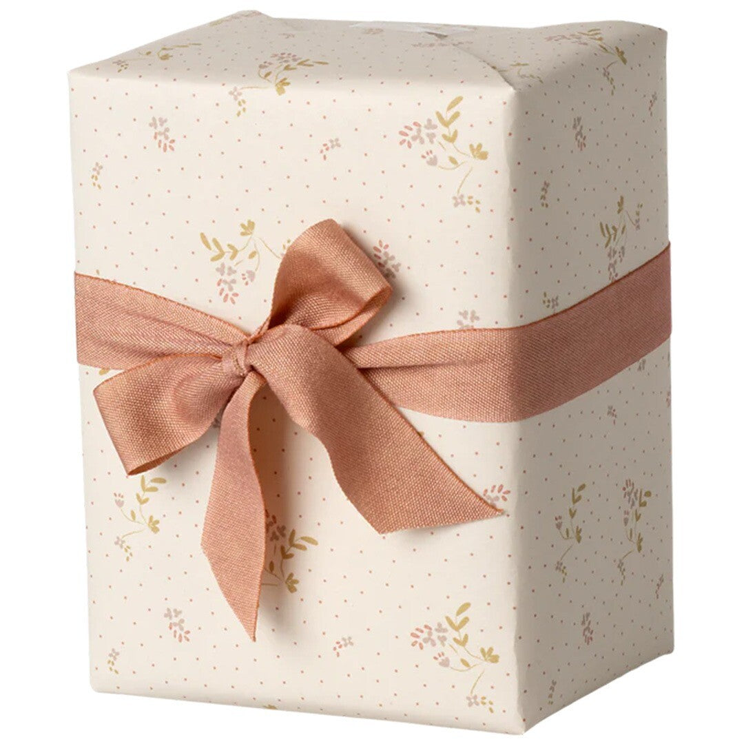 Een ingepakt cadeau met Maileg inpakpapier met beige bloemetjes en stippen, omwikkeld met een roze lint.