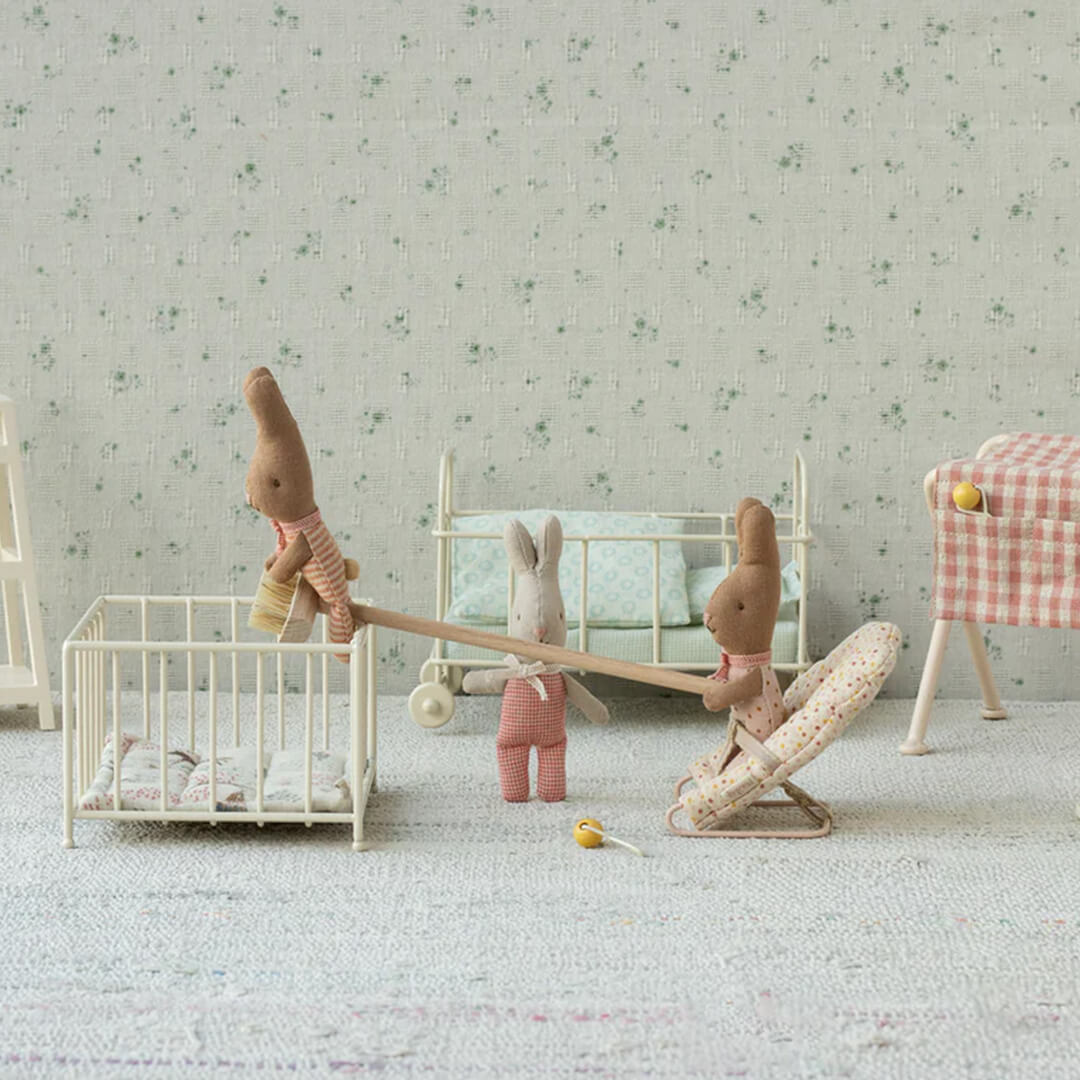 Drie Maileg pluchen konijnen spelen met een wipwap en miniatuurmeubels in een speelkamer.