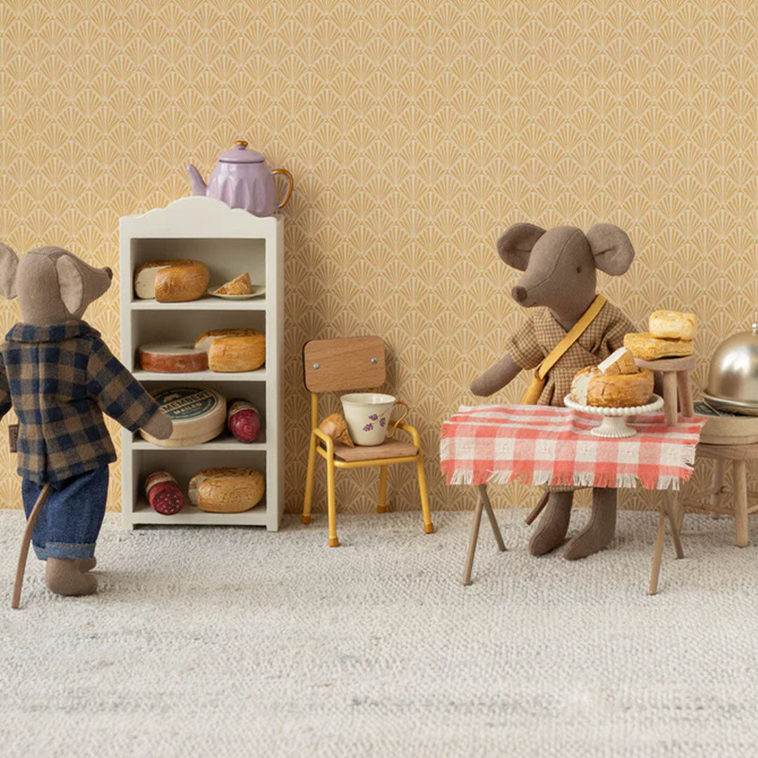 Twee Maileg knuffelmuizen in een miniatuur kaaswinkel met kazen op een plank en een tafel met geruit kleed.