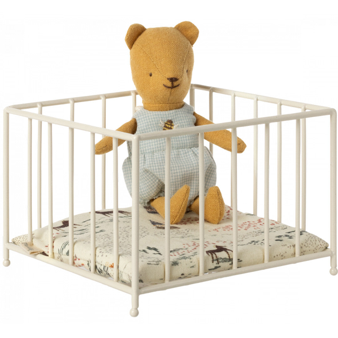 Maileg poppenbabybox met een berenpop in een blauwe romper op een matrasje met dierenpatroon.