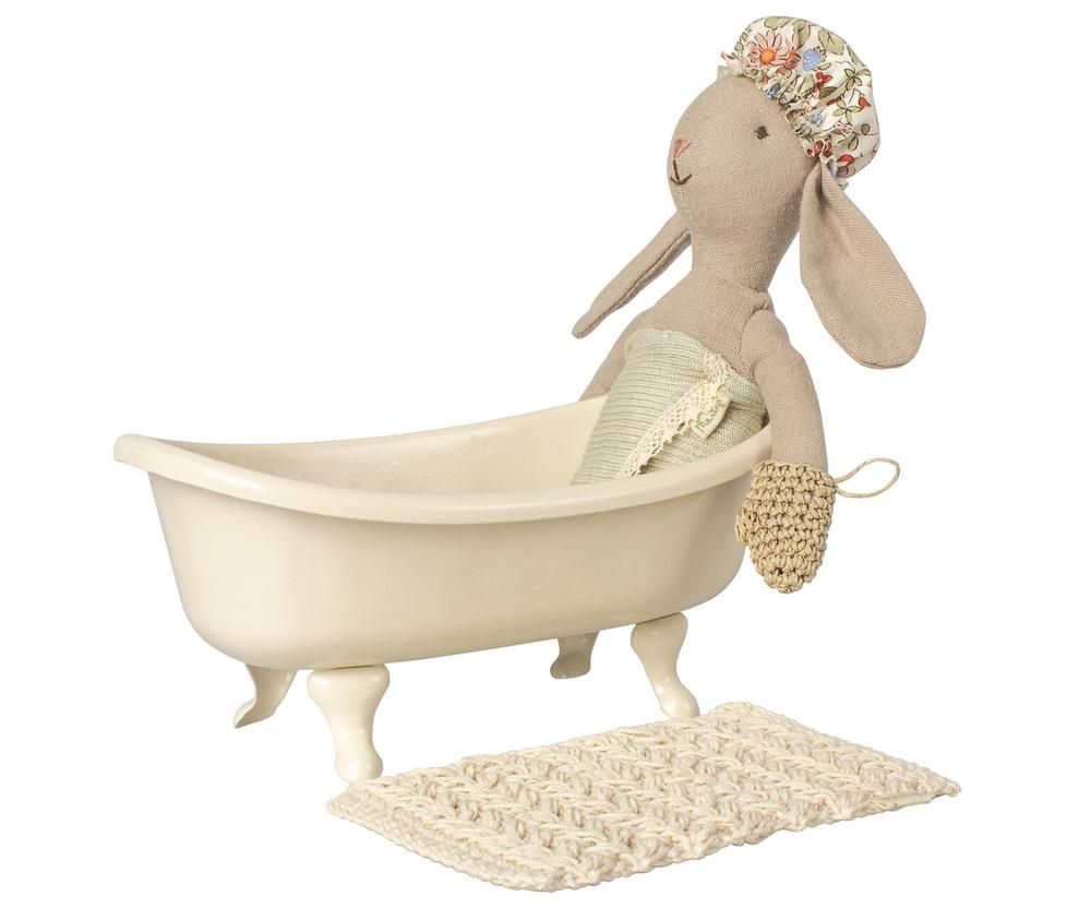 Maileg konijnenpop zit in een beige poppenhuis badkuip met een badmatje ernaast.