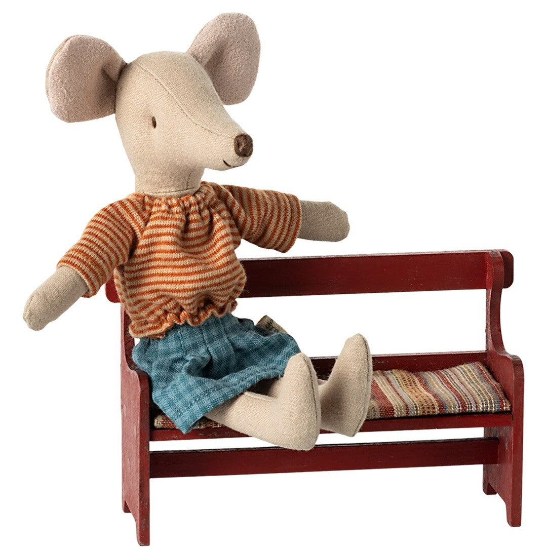 Maileg muispop zit op het rode houten poppenhuisbankje met gestreept kussen.
