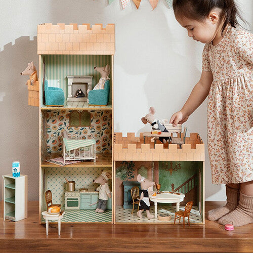 Een meisje speelt met een Maileg poppenhuis, waarbij de beige bijzettafel met een muispop in een van de kamers staat.