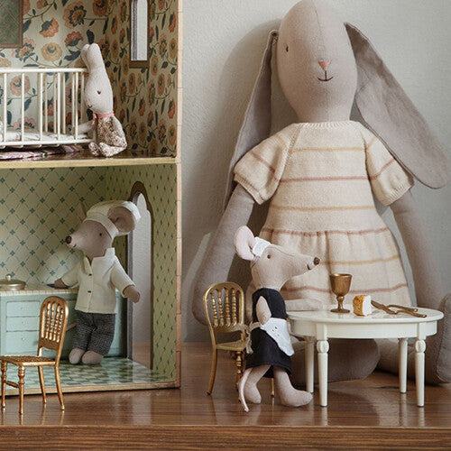 Twee Maileg muizenfiguren zitten aan een beige ovale poppenhuis eettafel.