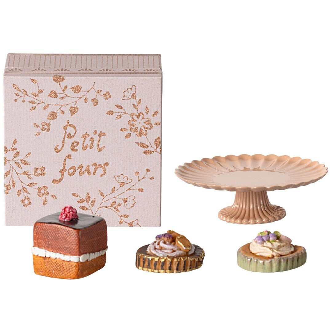 Maileg poppenhuis gebakjes en taartplateau, met een roze doos met 'Petit fours' tekst en drie gebakjes naast een roze taartplateau.