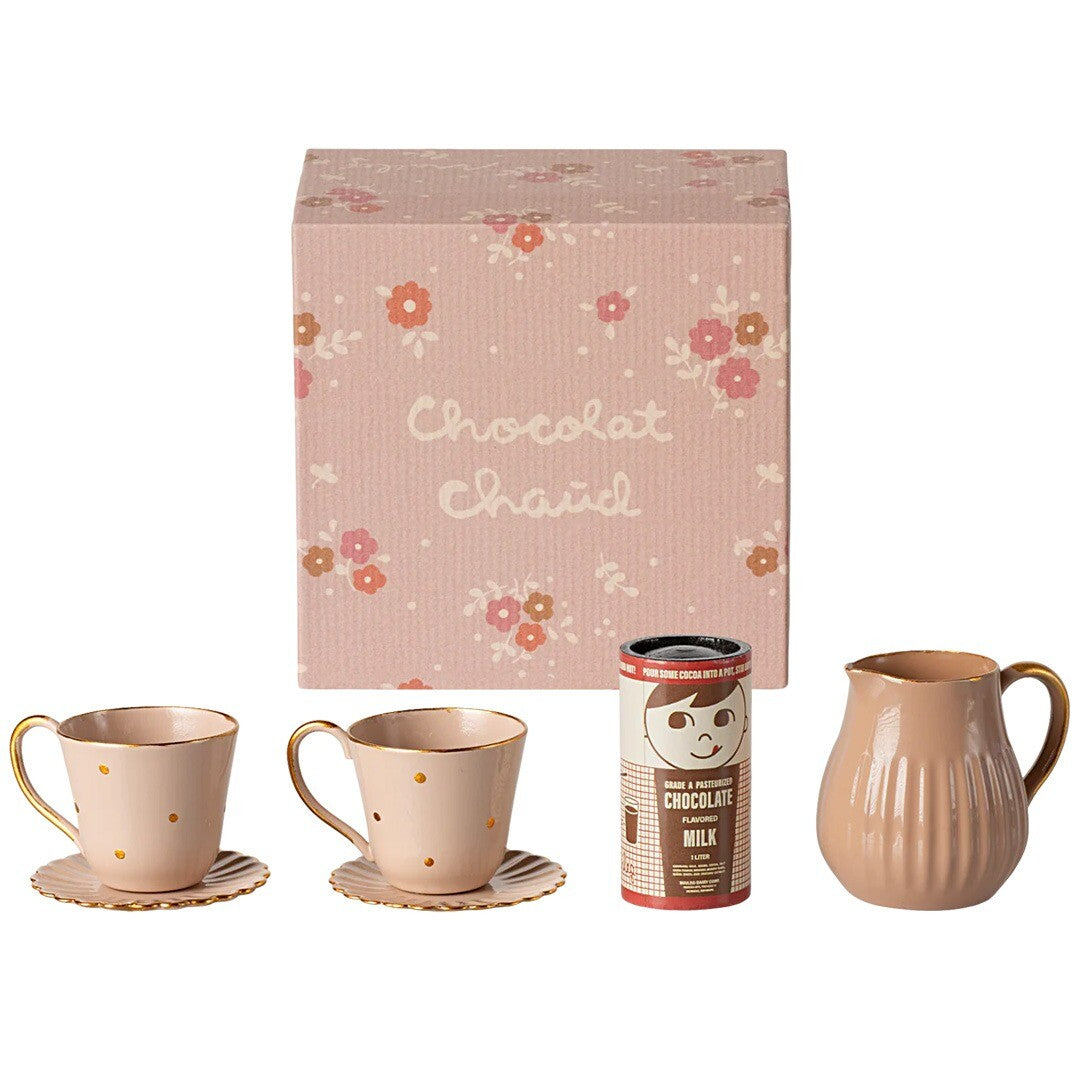 Maileg poppenhuis warme chocolademelk set met twee kopjes, een melkkan en een pakje chocolademelk, naast de roze bloemige verpakking.