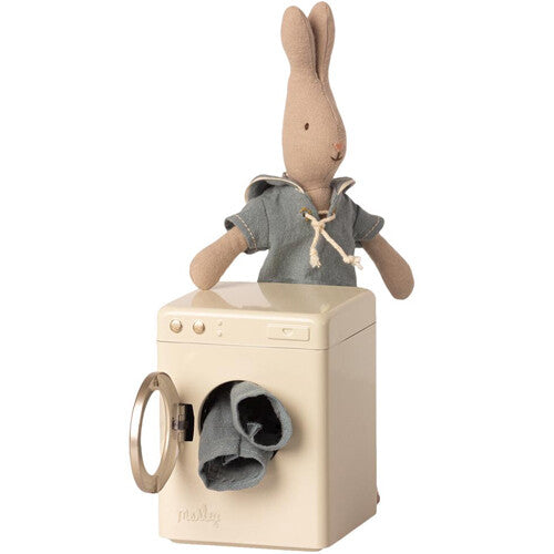 Maileg poppenhuis wasmachine met open deur en een konijn pop in een blauw shirt erachter.