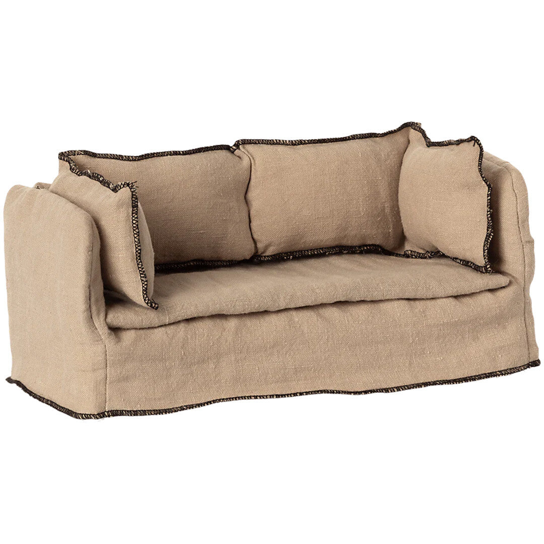 Maileg beige stoffen poppenhuisbank met donkere stiksels, schuin van voren gefotografeerd.