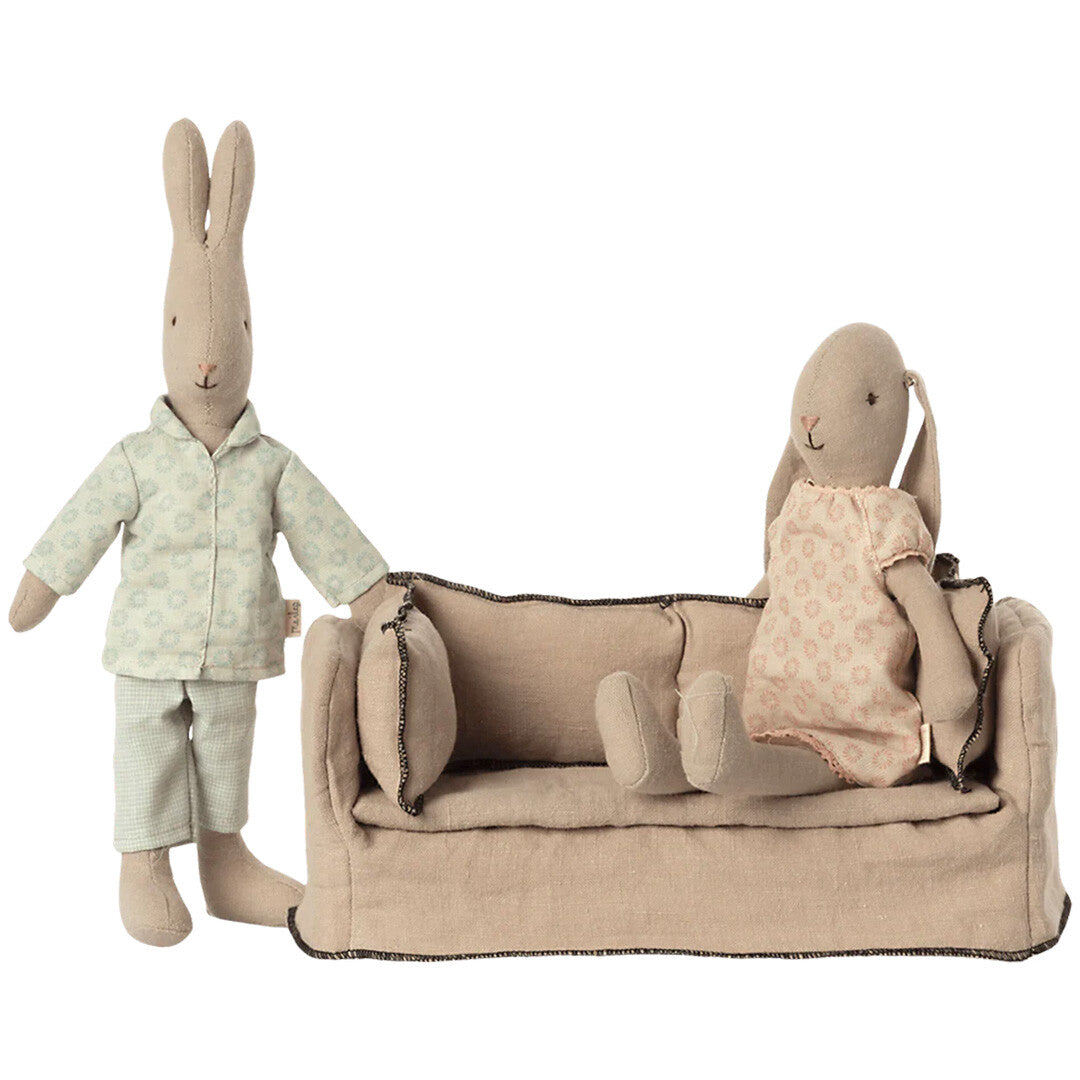 Maileg beige stoffen poppenhuisbank met een staand en een zittend Maileg konijn ernaast en erop.