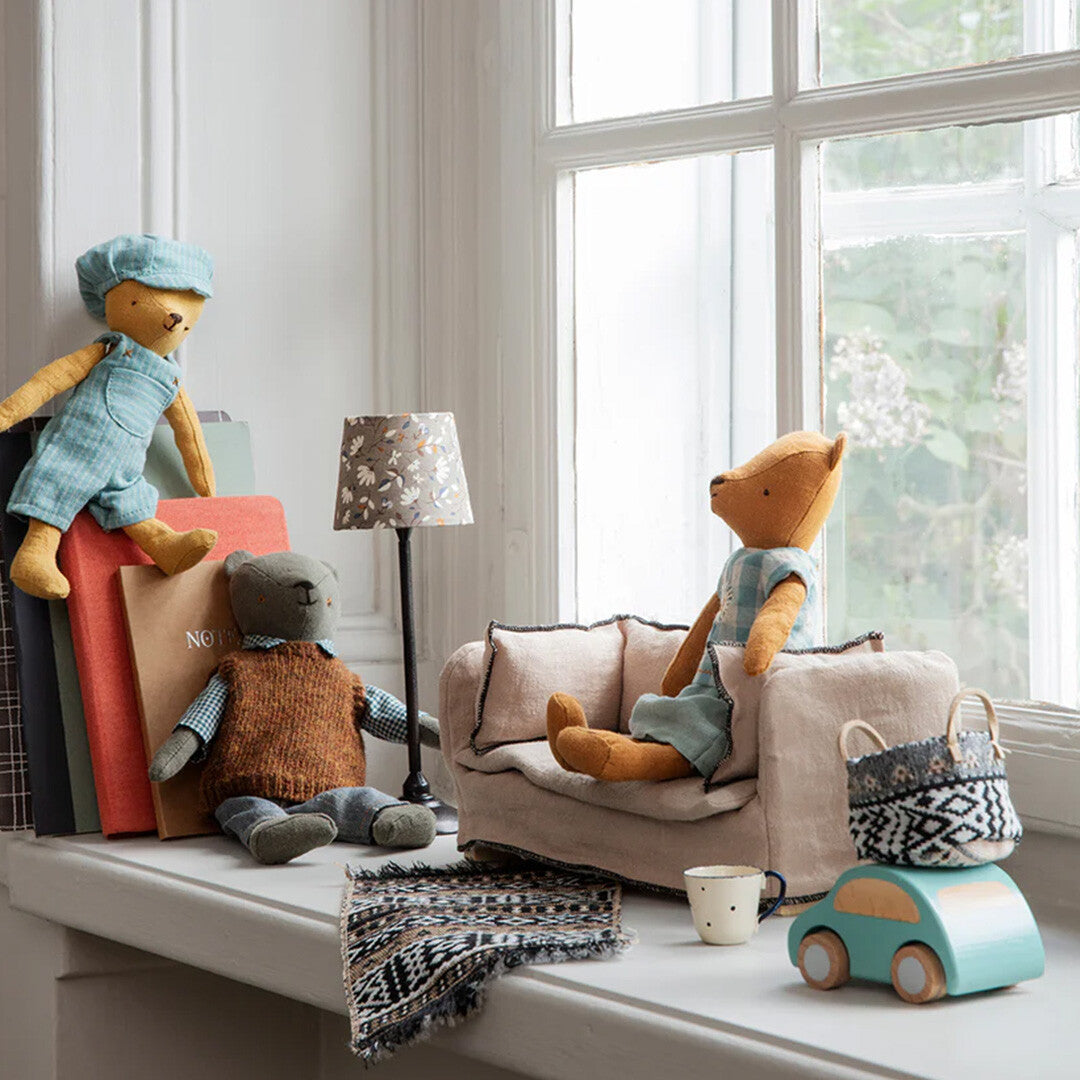 Maileg poppenhuisbank in een speelscène op een vensterbank met knuffels en accessoires.