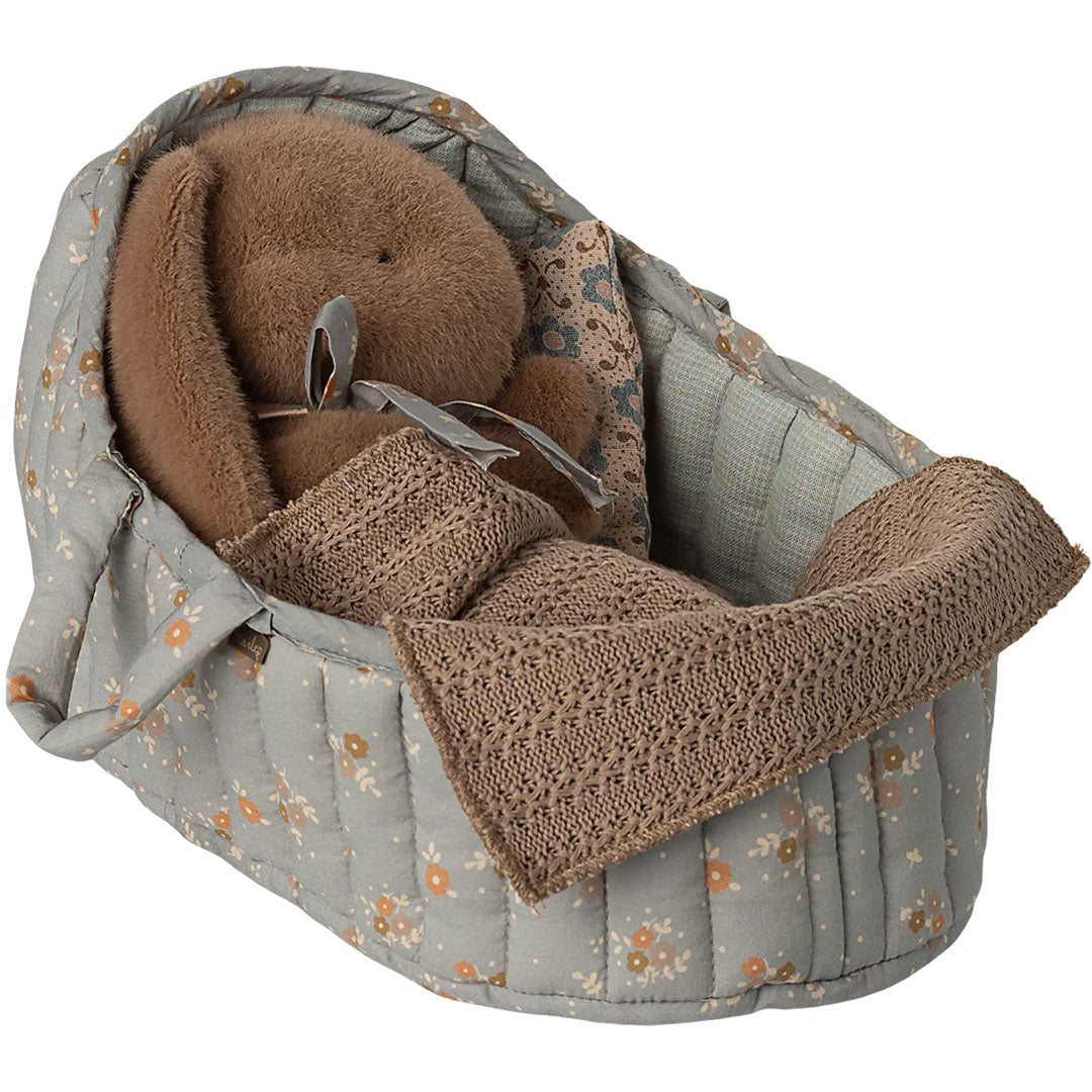 Maileg poppenreiswieg met blauw gebloemd patroon, met een bruine konijn knuffel en een gebreide deken.