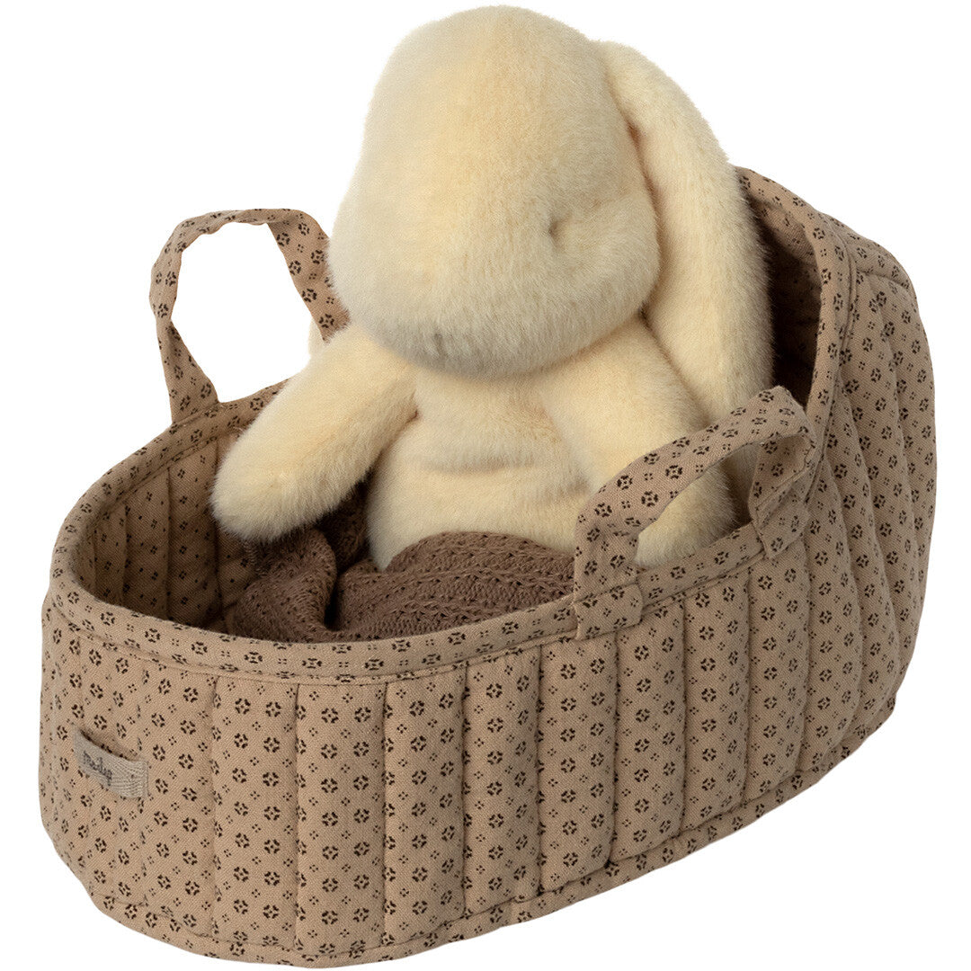 Maileg poppenreiswieg met een lichtgele pluchen konijnpop erin, deels bedekt met een bruine deken.