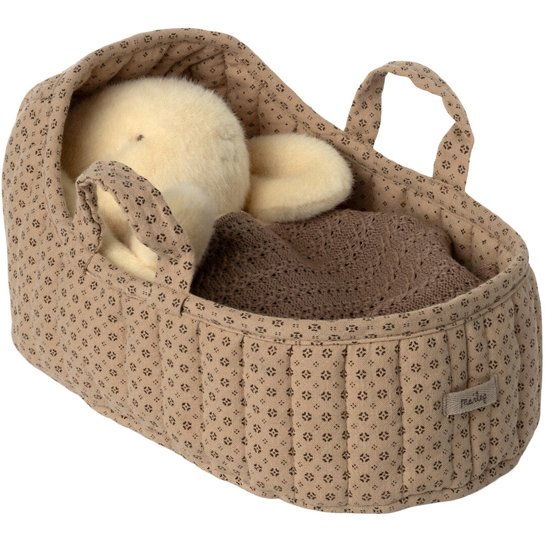 Maileg poppenreiswieg met een lichtgele pluchen konijnpop die slaapt onder een bruine deken.