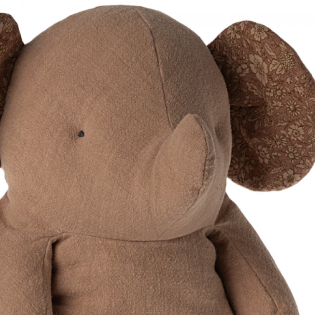 Detail van de kop van de bruine pluchen olifant met gebloemde oren.