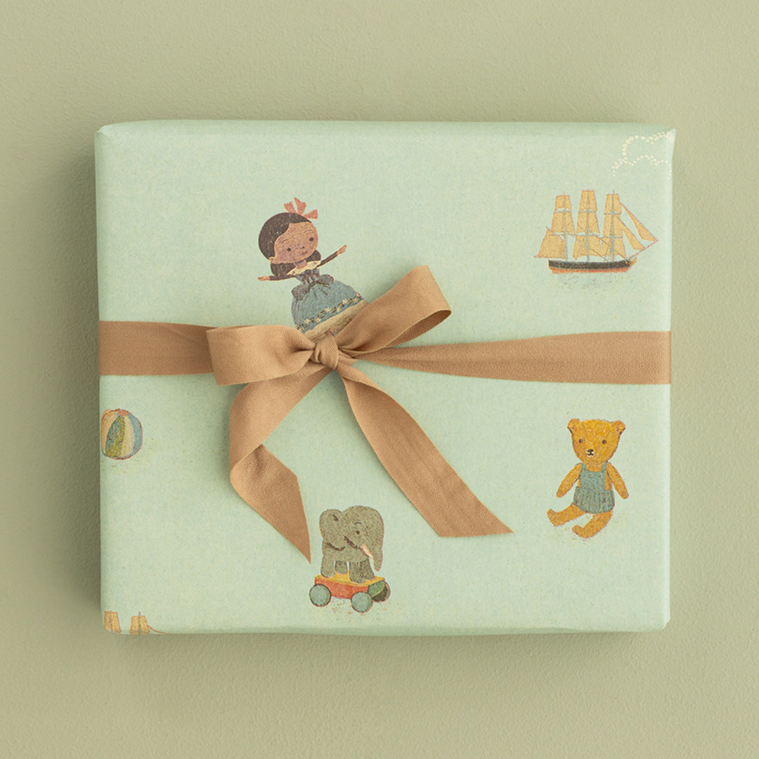 Een ingepakt cadeau met Maileg inpakpapier en een bruine strik, van bovenaf gezien.