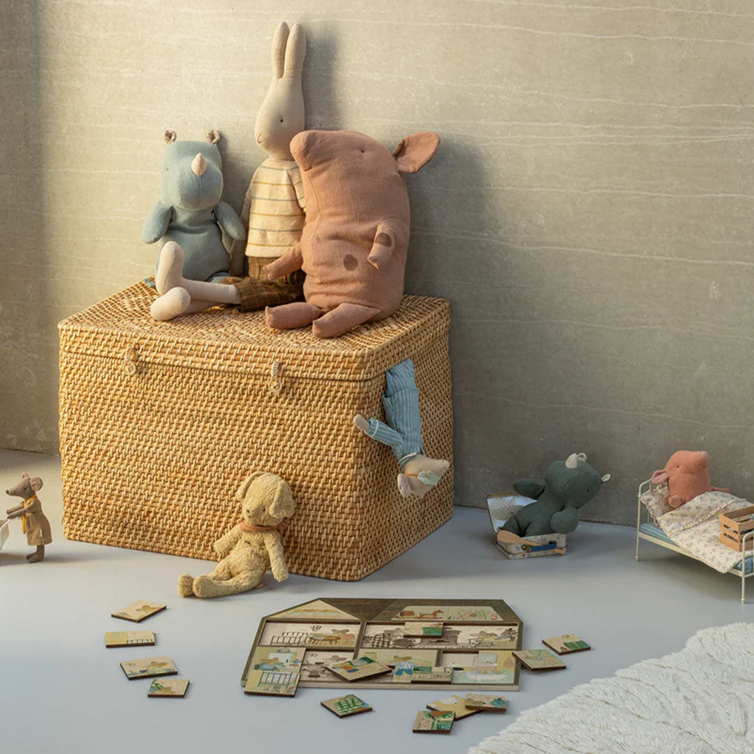 Maileg houten puzzel van een muizenhuis ligt op de grond, omringd door verschillende Maileg knuffels en een rieten mand.