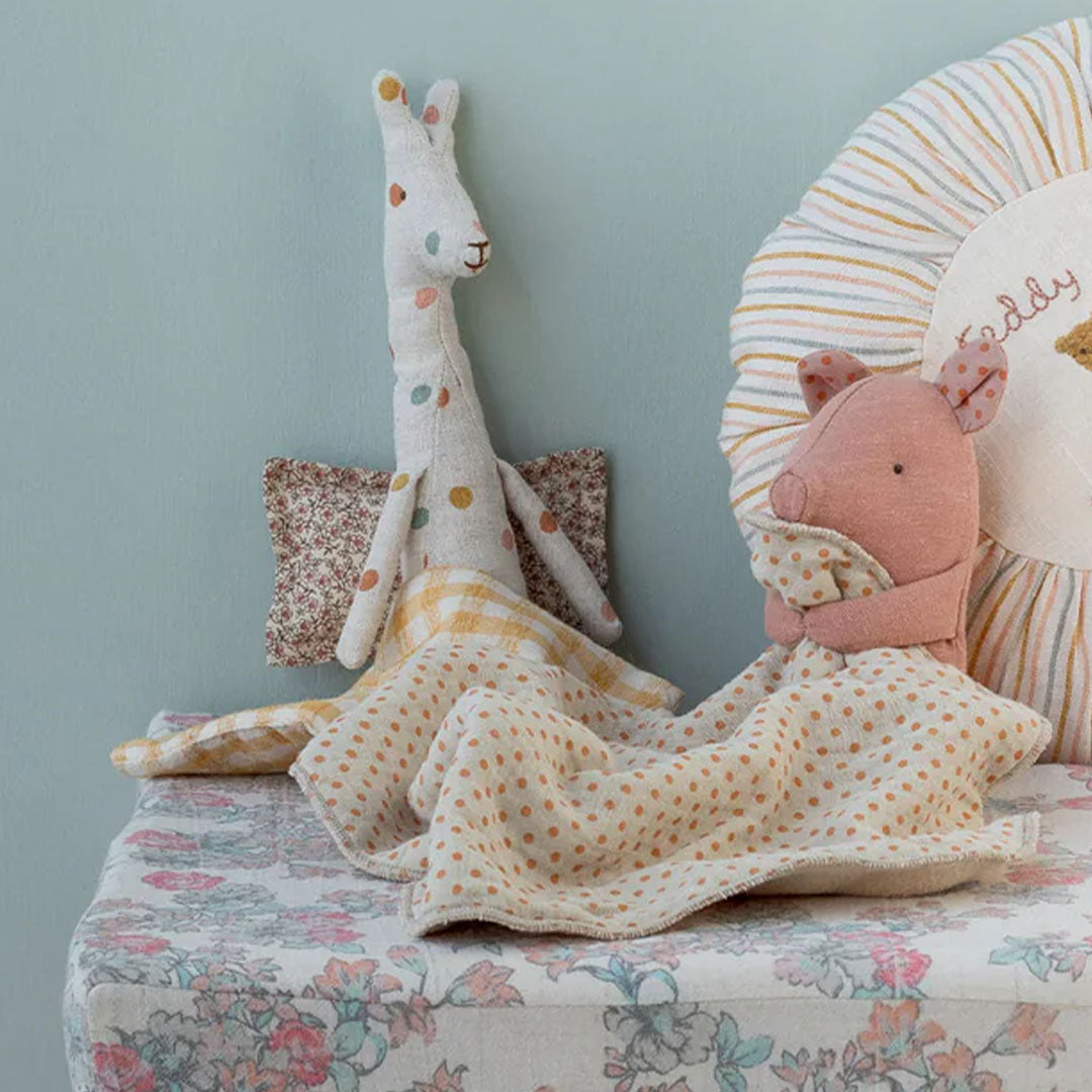 Maileg knuffeldoek biggetje en een giraffe knuffel staan op een commode in een babykamer.