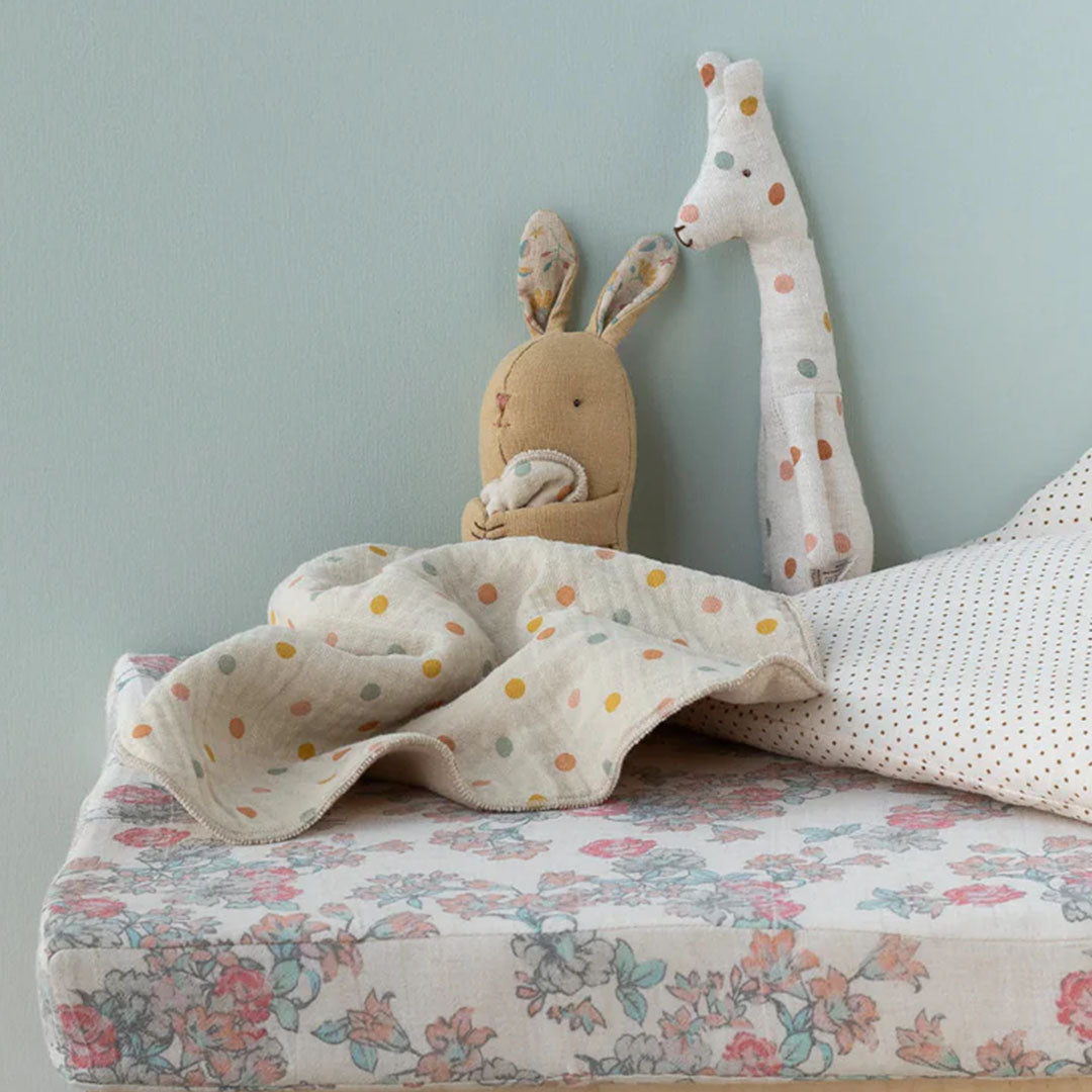 Maileg knuffeldoek konijn en een pluchen giraffe op een commode met een stippendeken.