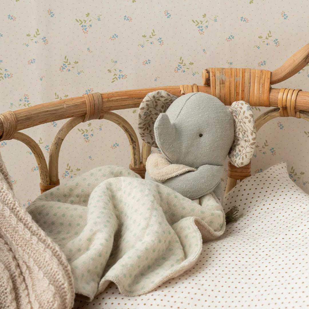 Maileg knuffeldoek olifant op een bedje met een rieten hoofdeinde.