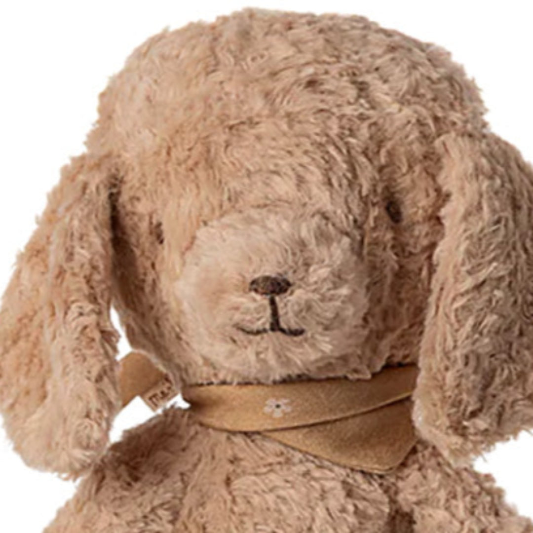 Detailopname van de kop van de beige pluchen poedel knuffel met zijn gezicht en bandana.