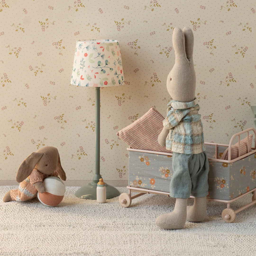 Twee Maileg knuffelkonijnen in een kinderkamer, één zit met de bal en de ander staat bij een poppenwagen.