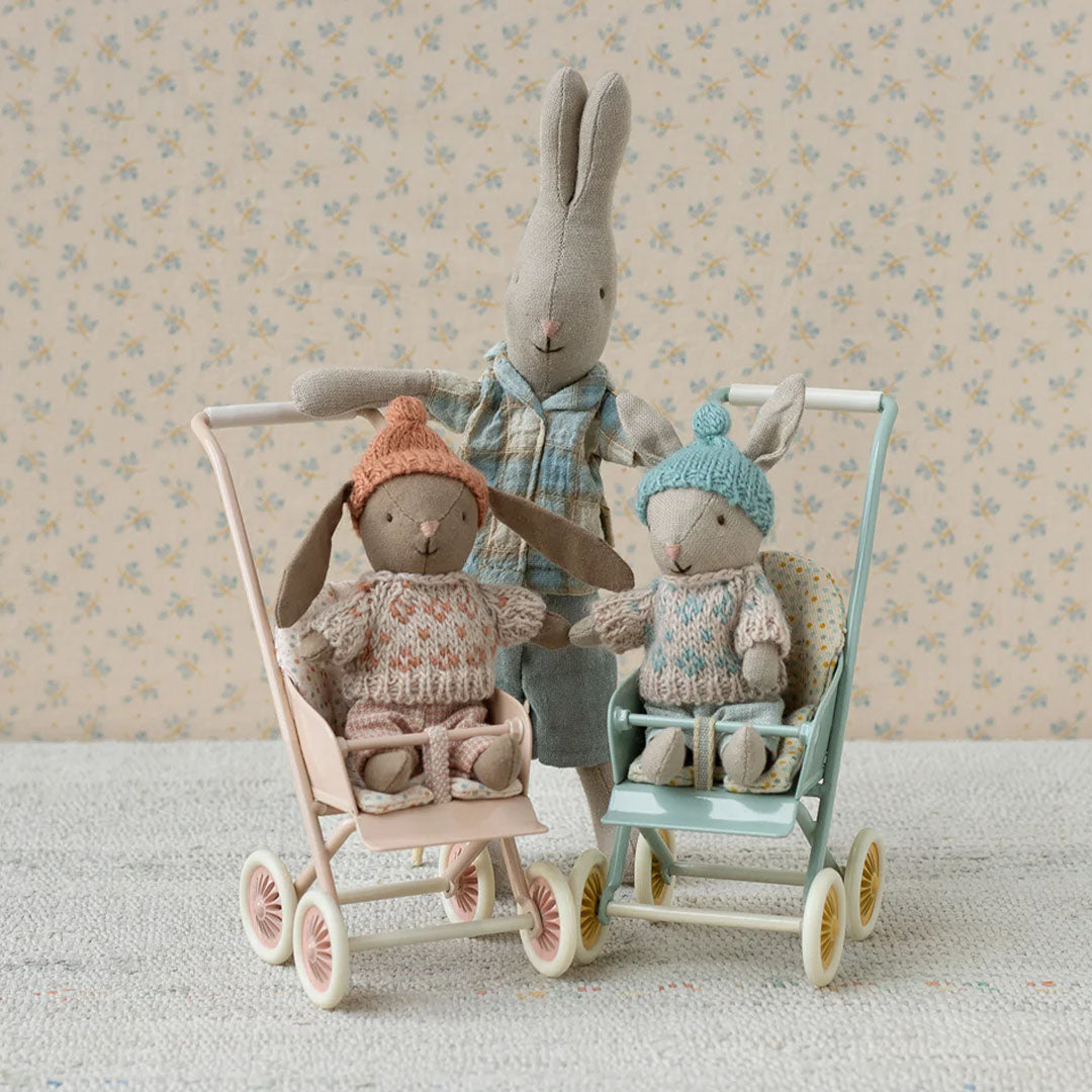 Maileg knuffelkonijnenfamilie met twee kleine konijnen in kinderwagens en een groter konijn erachter.