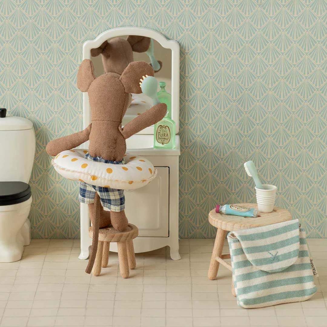 De Maileg knuffelmuis staat op een krukje voor een spiegel in een miniatuur badkamer.