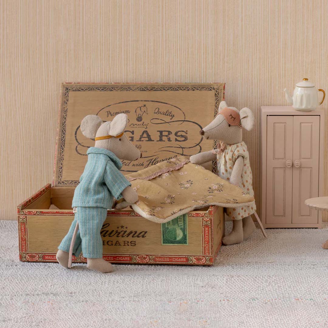 Twee Maileg knuffelmuizen in pyjama bij een open doos, in een miniatuur slaapkamer setting.
