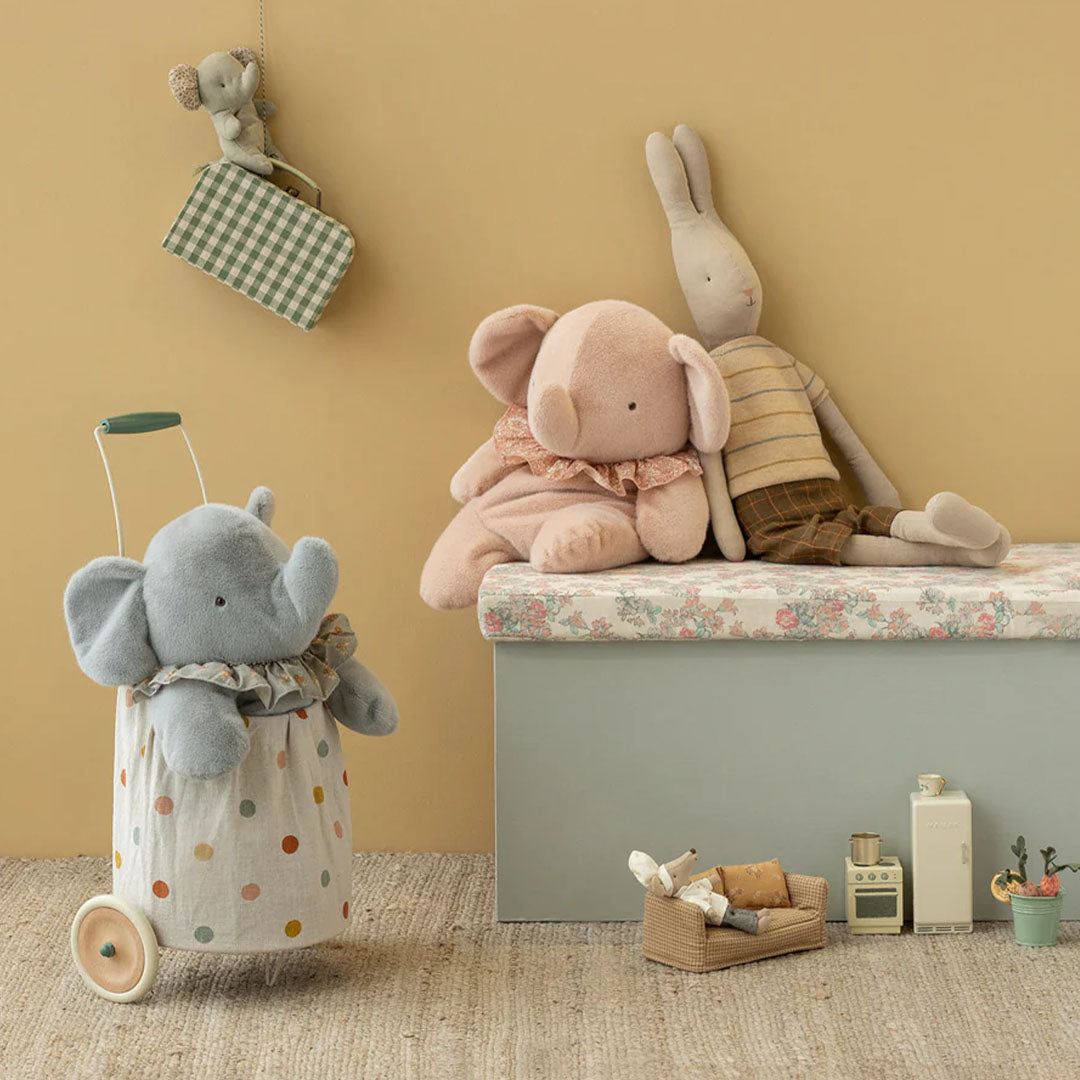 Maileg pluchen olifant en konijn zitten op een bankje, met een grijze olifant in een trekkar en een muis aan de muur.