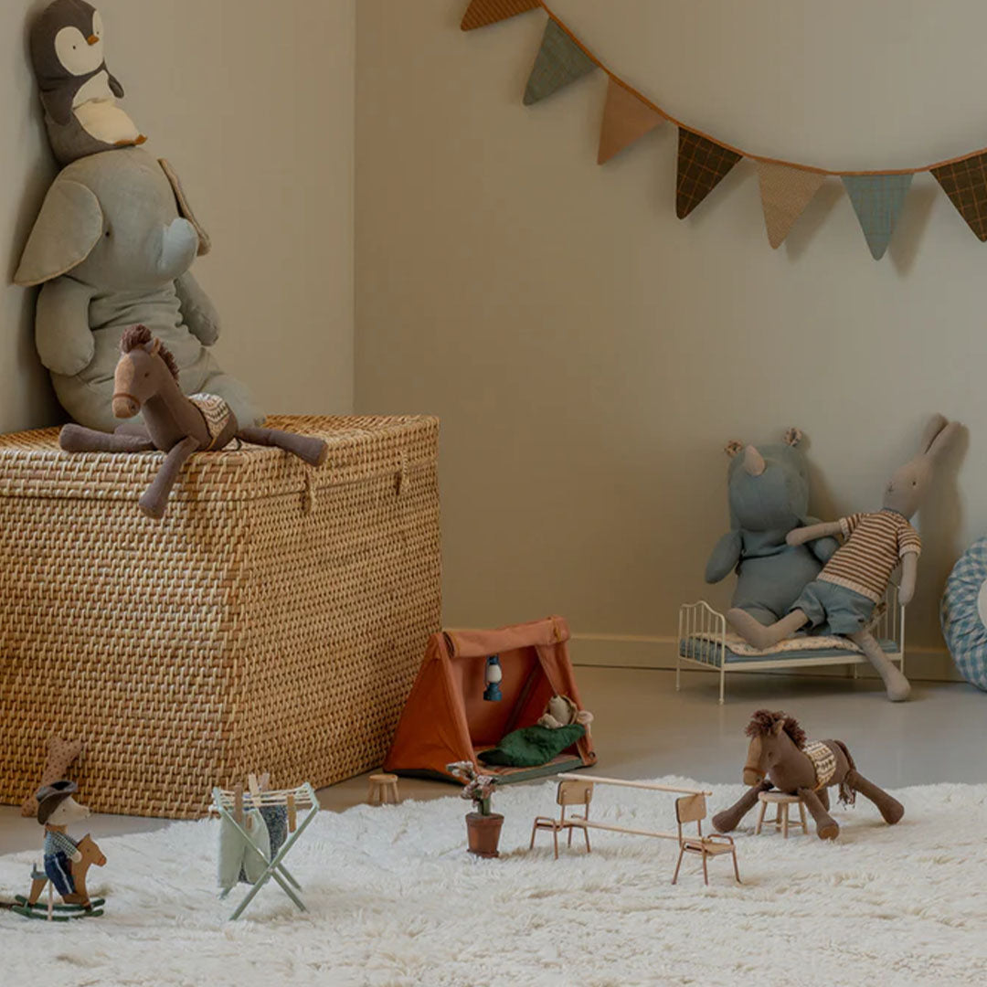 Een speelkamer met diverse Maileg knuffels en miniatuurmeubels op een wit vloerkleed.