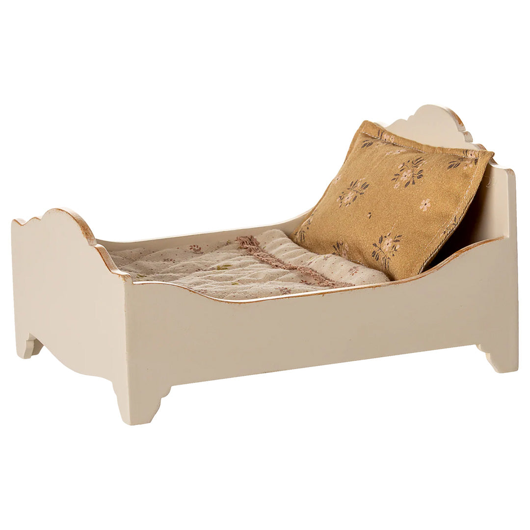 Maileg off-white houten poppenbed met gebloemd kussen en deken, schuin van voren rechts gefotografeerd.