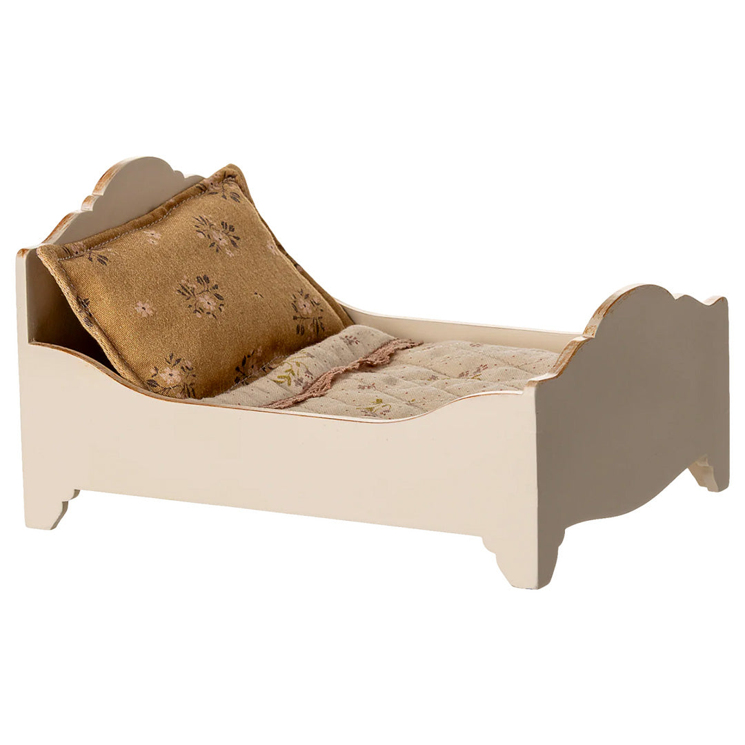 Maileg off-white houten poppenbed met gebloemd kussen en deken, schuin van voren links gefotografeerd.