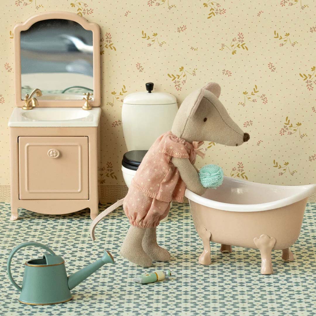 Maileg muis in pyjama wast zich in een roze poppenhuis badje, met een wastafel en toilet op de achtergrond.