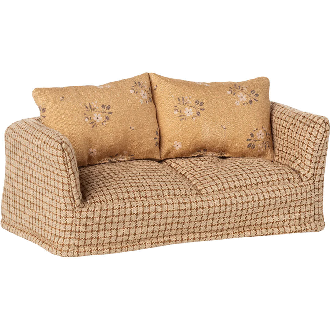 Maileg poppenhuis bankje met beige geruite bekleding en twee gebloemde kussens, schuin van voren gefotografeerd.