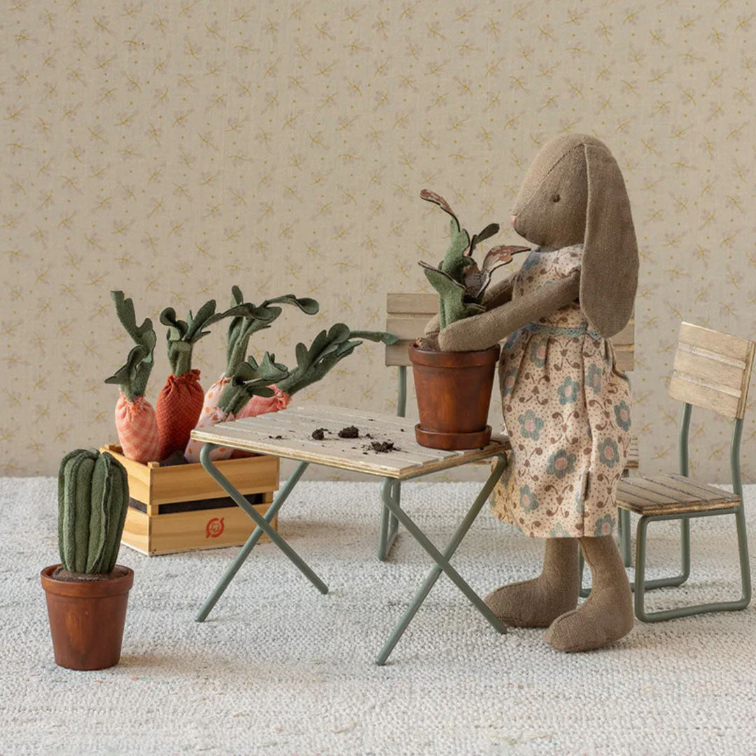 Maileg poppenhuis bloempot met cactus op de vloer naast een konijn dat een plant verpot.