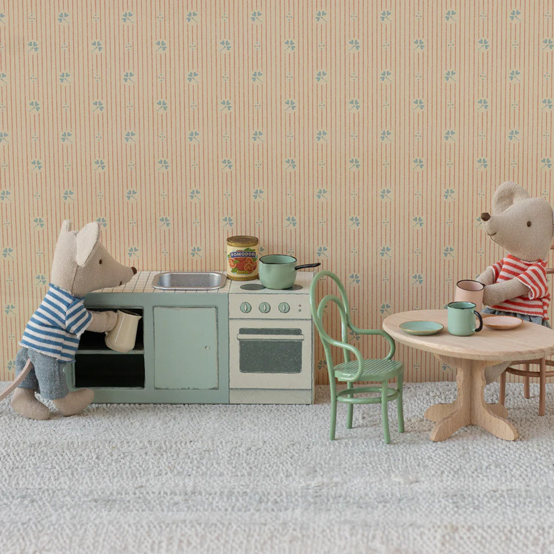 Twee Maileg muizenpoppen spelen met de poppenhuis keukenspeelset in een kamer met een tafel en stoel.