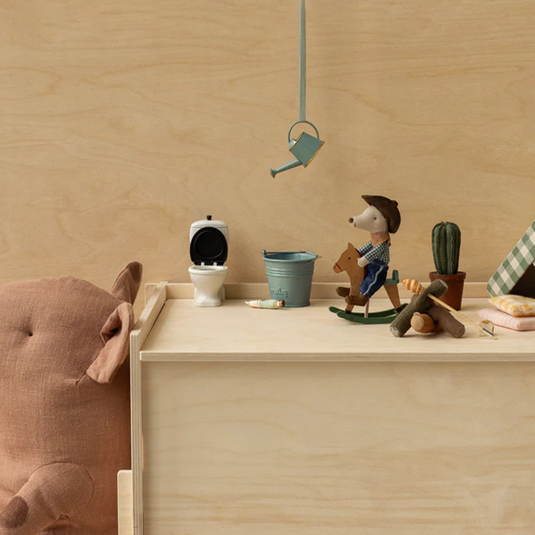 Maileg muisfiguur op een houten hobbelpaard in een poppenhuis scène.