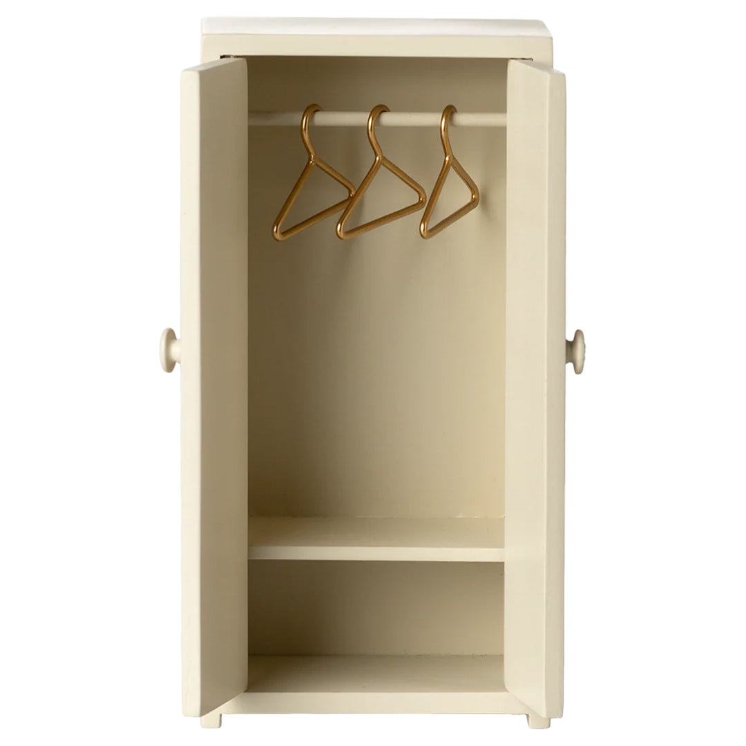 Maileg poppenhuis kledingkast in crème kleur met open deuren, een hangroede en drie gouden hangers.