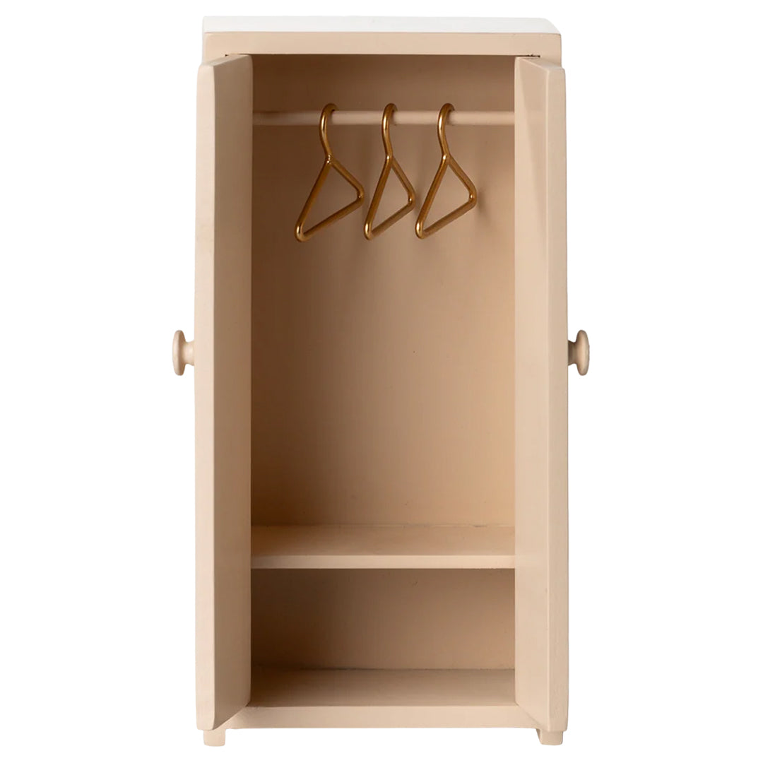 Maileg lichtroze poppenhuis kledingkast met open deuren, een hangroede met drie hangers en een plank.