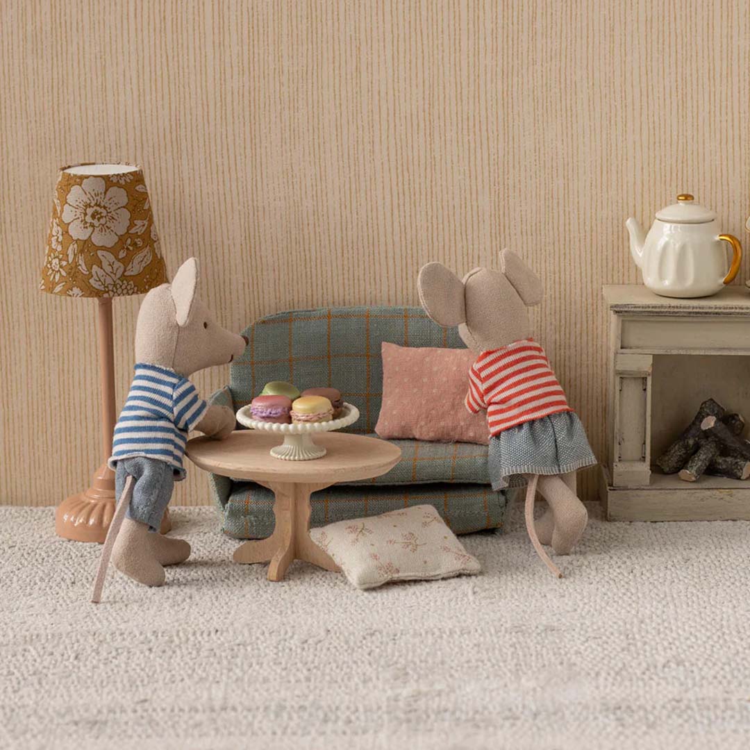 Twee Maileg muizenpoppen staan bij de houten poppenhuis koffietafel met macarons in een poppenhuis woonkamer.