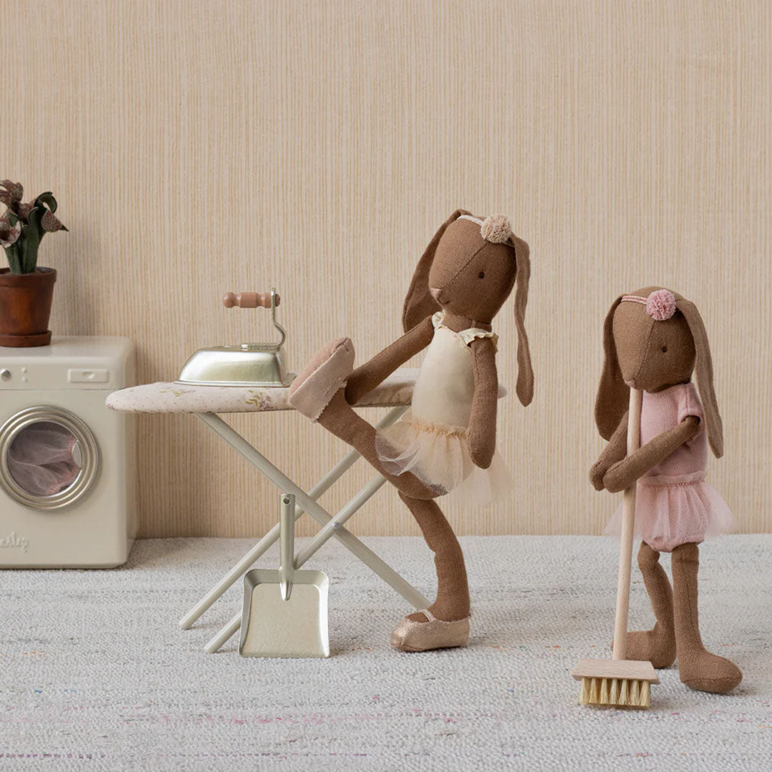 Twee Maileg konijnenpoppen in een kamer met de poppenhuis strijkplank, een wasmachine en een bezem.